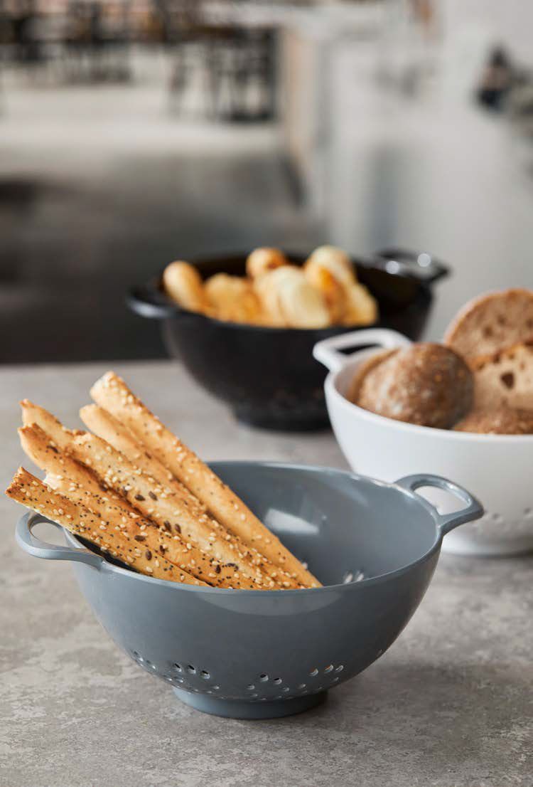 Due ciotole grigie contenenti grissini e panini su un bancone della cucina.