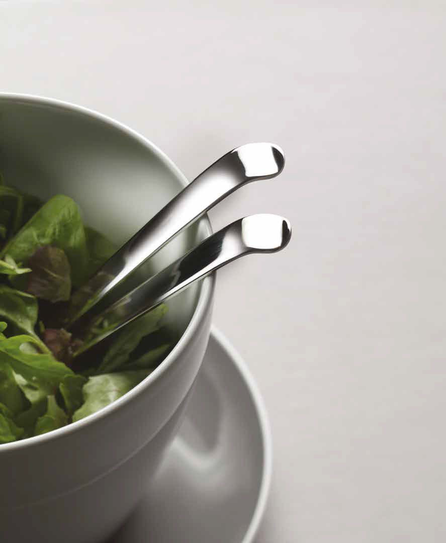 Due pinze di metallo appoggiate in una ciotola bianca di insalata verde su una superficie grigia
