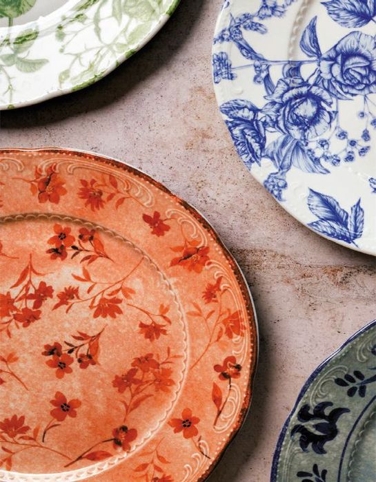 Piatti colorati con motivi floreali sovrapposti su una superficie beige