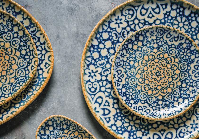 Piatti in ceramica con motivi blu e oro su una superficie grigia