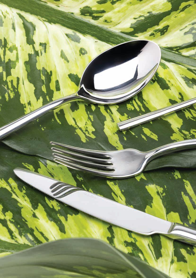 Cucchiai, forchette e un coltello su uno sfondo di stoffa verde con motivi di foglie.