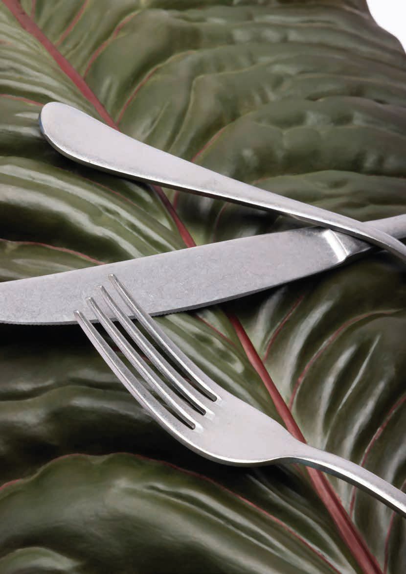 Forchetta e coltello su una tovaglia verde con motivo a foglie.