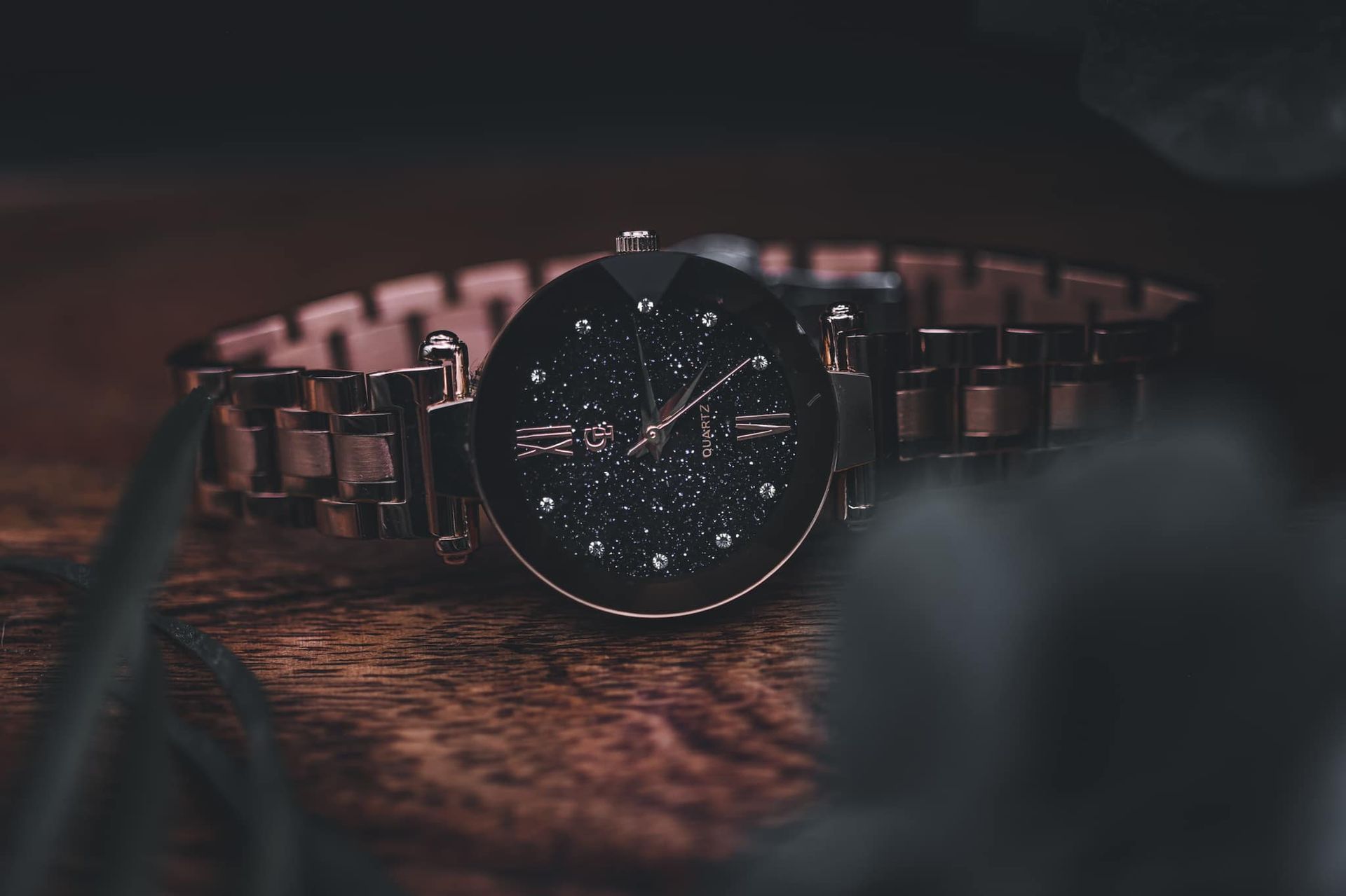 Rose gold wristwatch with black face, featuring stars.