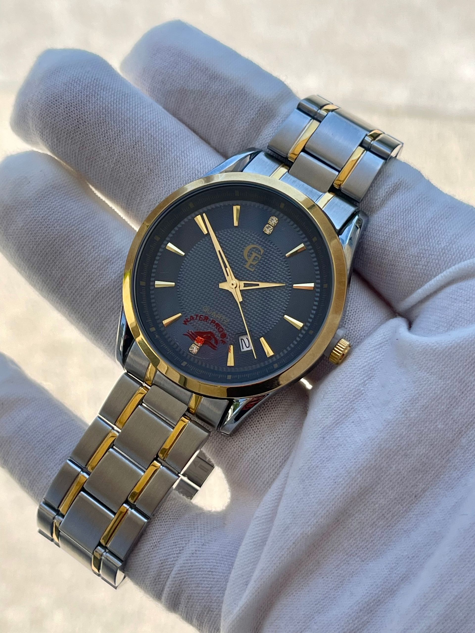 Silver and gold wristwatch with a black face resting on a white-gloved hand.