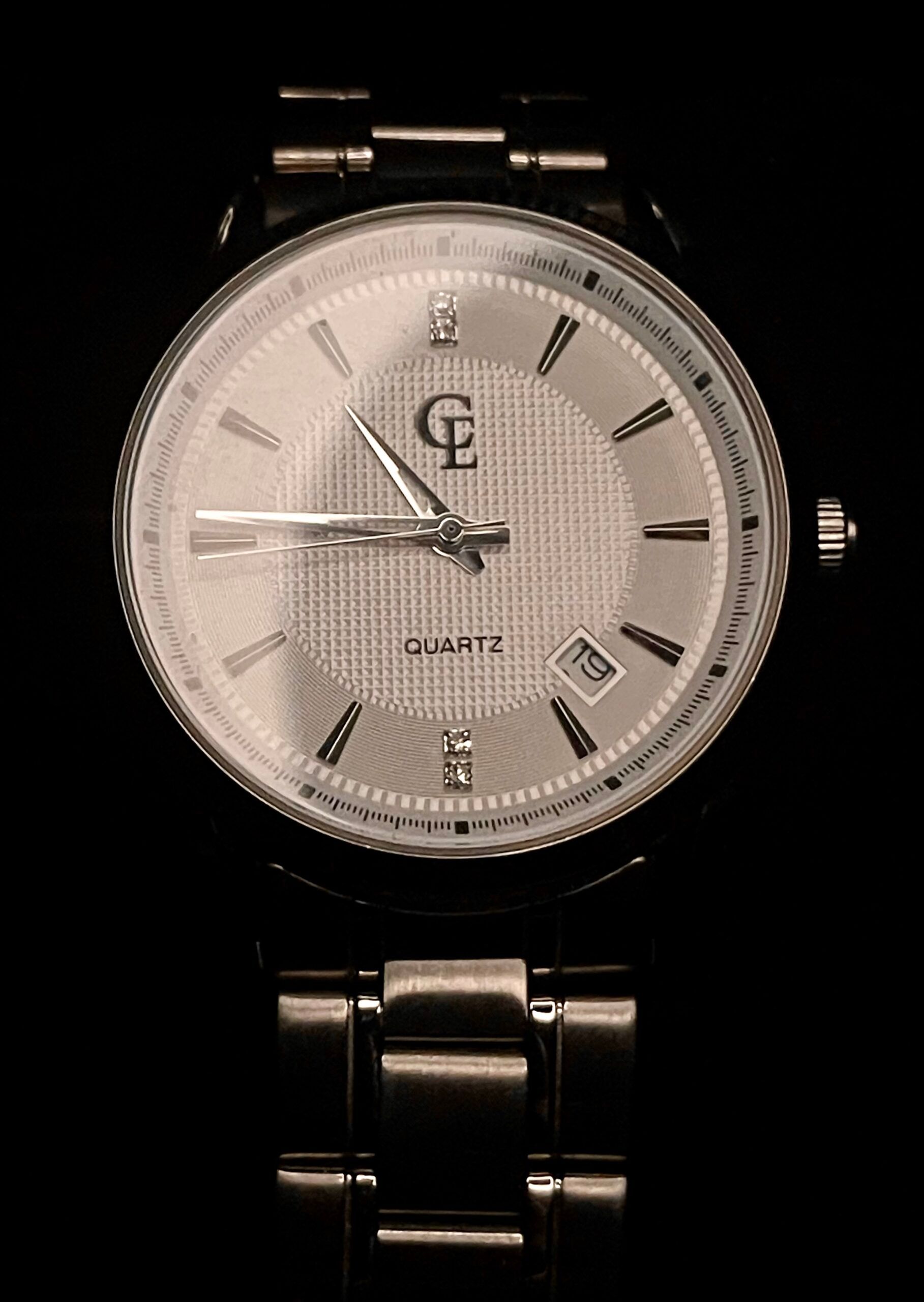 Silver wristwatch with a textured face and metal band.