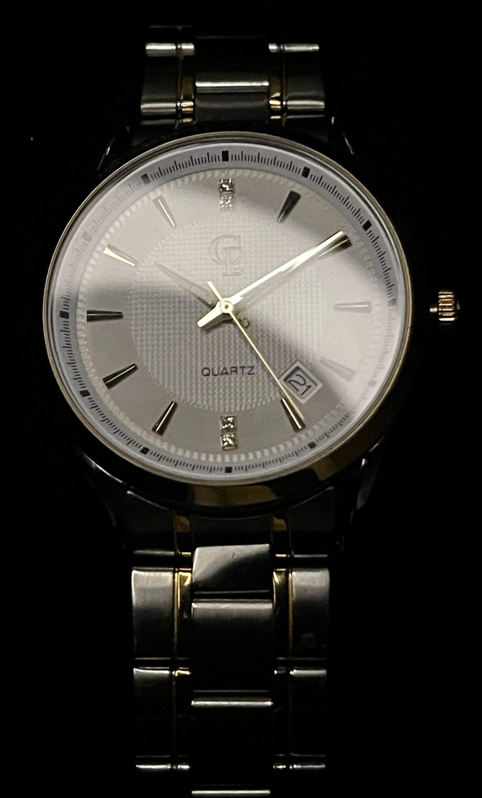 Silver wristwatch with gold accents and a black band, against a black background.