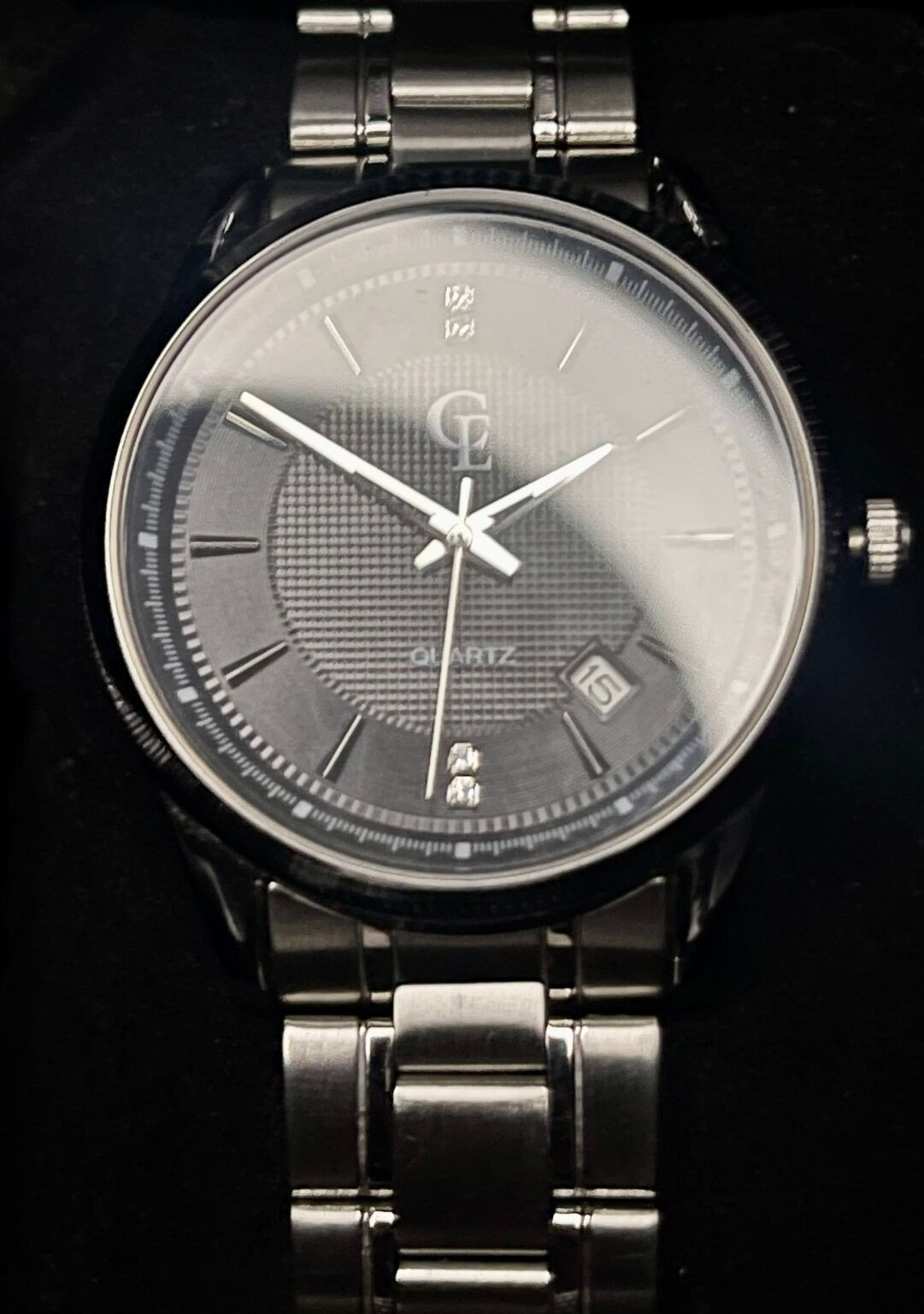 Silver wristwatch with a dark gray face, a date window, and a stainless steel band.