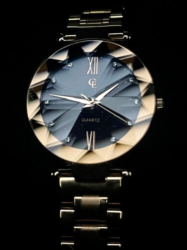 Gold wristwatch with a faceted bezel and blue dial; Roman numeral XII and VI are visible.