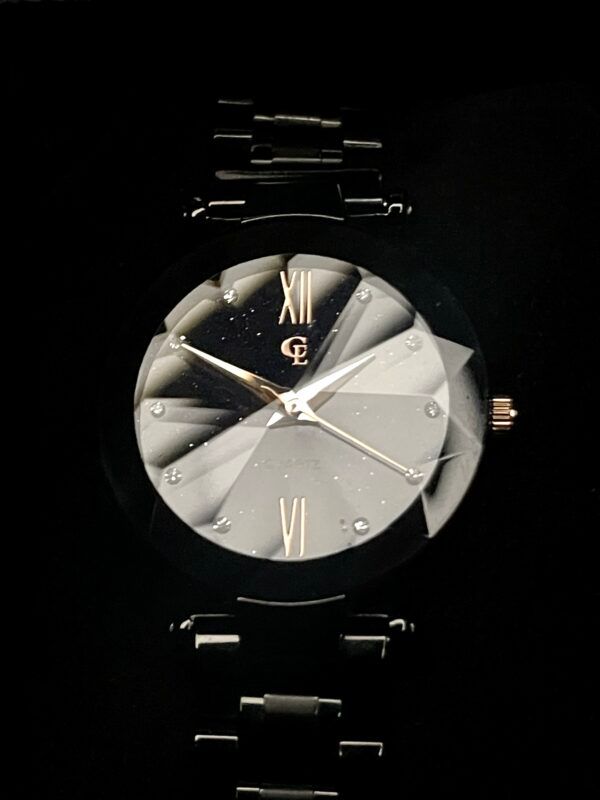 Black wristwatch with a faceted, silver-toned face, black band, and gold accents, against a black background.