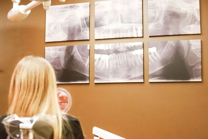 Dentist showing a dental model to a smiling patient in a dental office. Both are wearing gloves and masks. Dentist showing a dental model to a smiling patient in a dental office. Both are wearing gloves and masks.