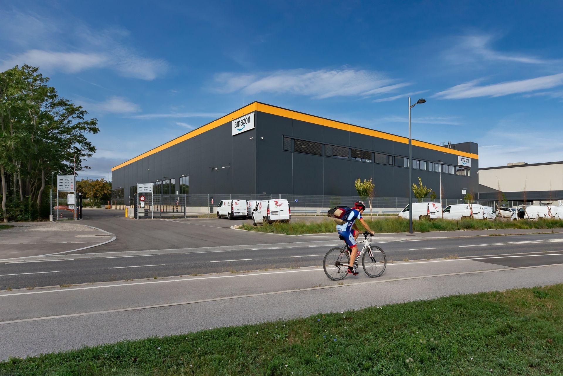A man is riding a bike in front of an amazon building