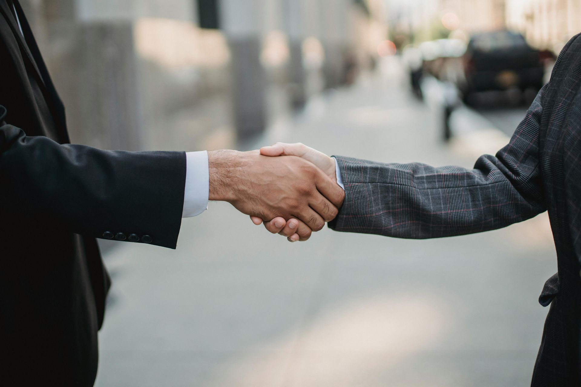 Two people in business suits shaking hands outdoors