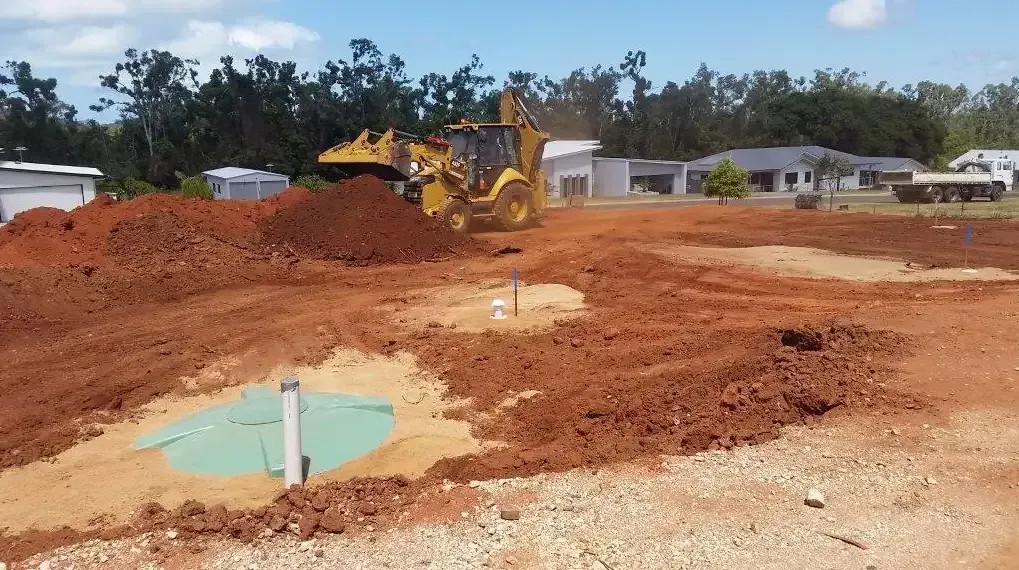 A Yellow Backhoe Operates on a Construction Site — Enviroplumb & Gas in Gracemere, QLD