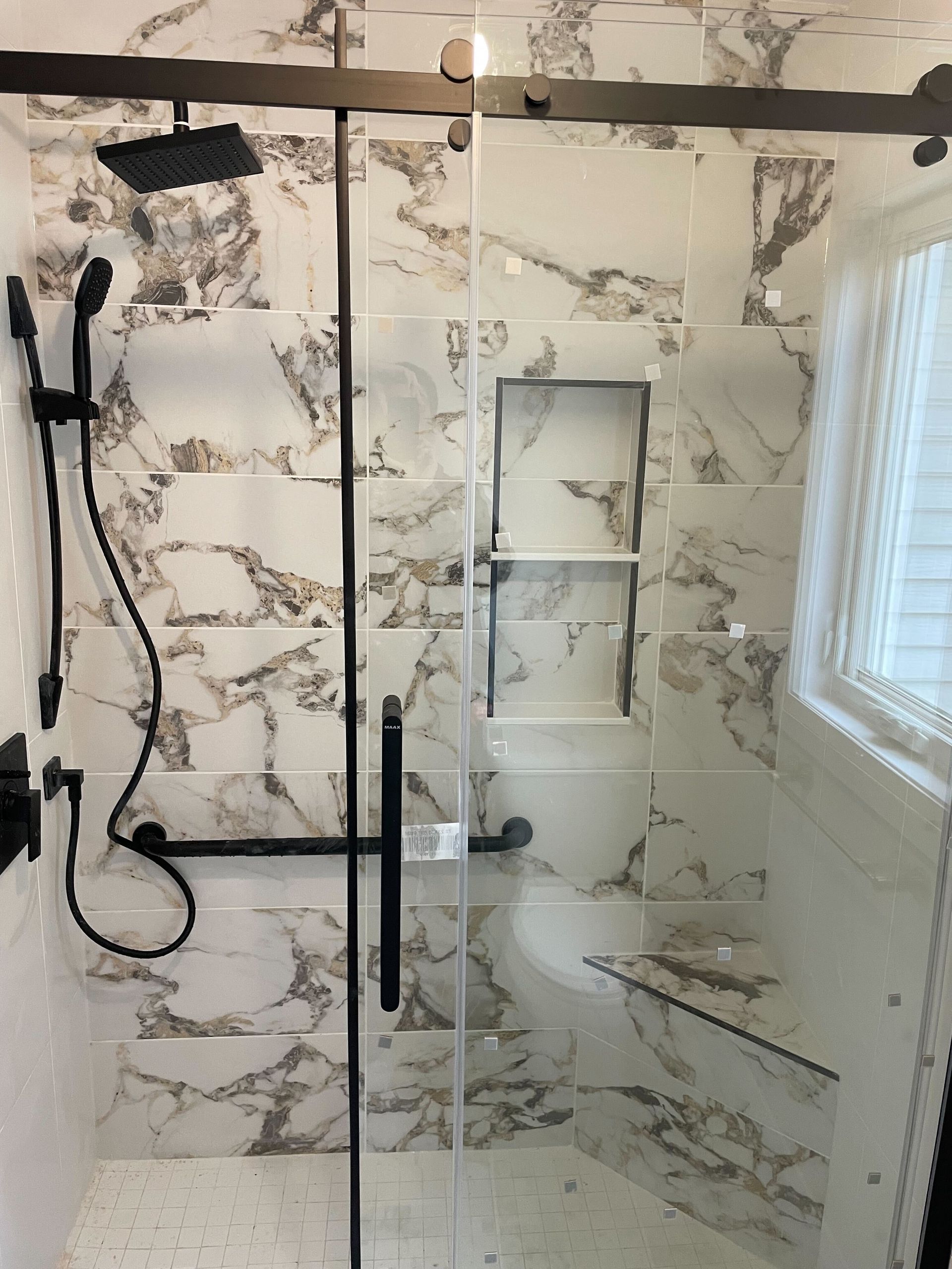 A bathroom with marble tiles and a sliding glass shower door.
