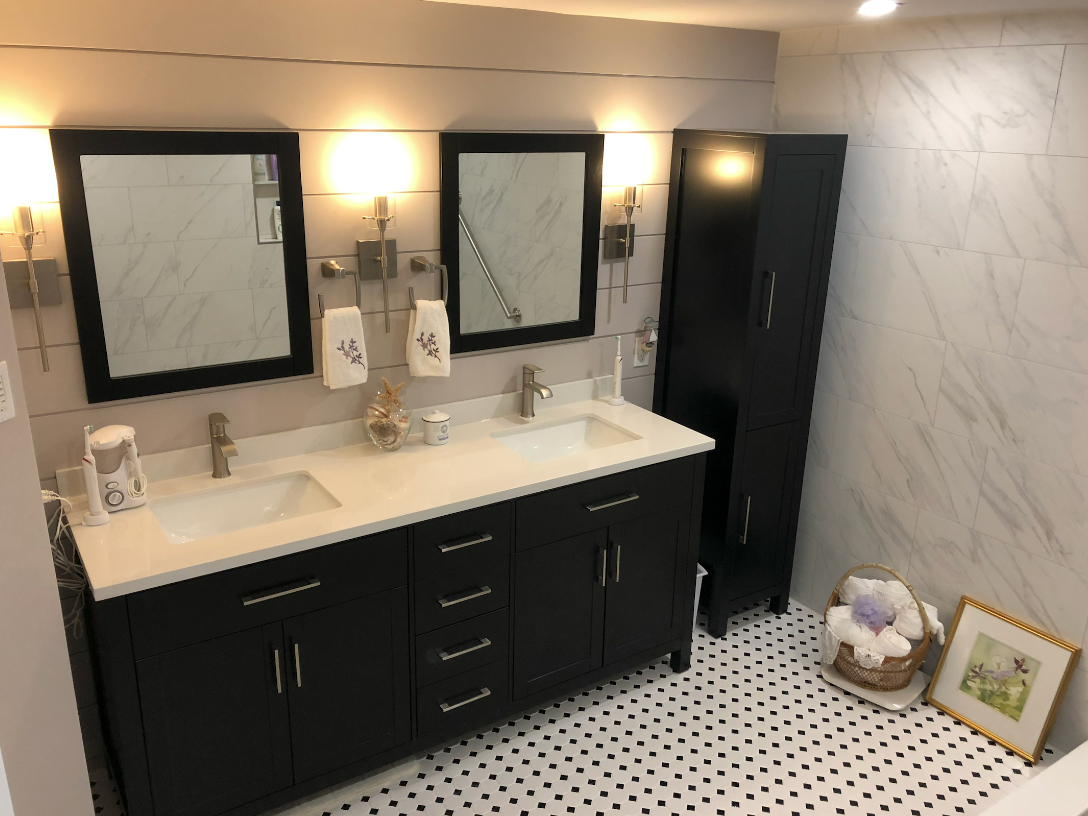 Black bathroom vanity with two mirrors, black cabinet, and black and white tile flooring.