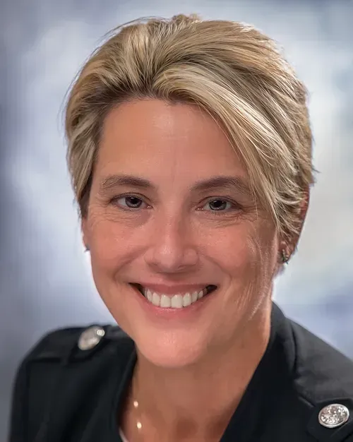 A woman in a black jacket is smiling for the camera.