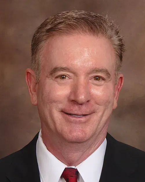 A man in a suit and tie is smiling for the camera.