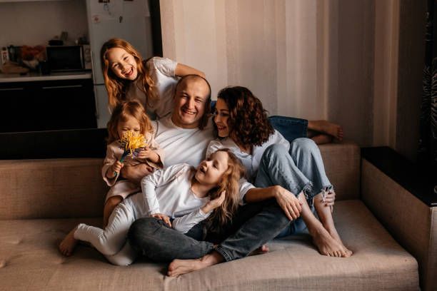 Family of five smiling, gathered on a couch indoors.