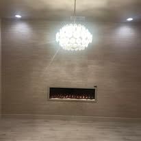 Modern lobby with wood-paneled wall, chandelier, and a long wall-mounted fireplace.