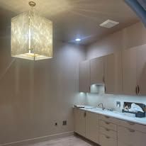 Modern laundry room with beige cabinets, white countertop, and a hanging cube pendant light