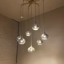Cluster of six clear glass pendant lights hanging from a ceiling in a beige room