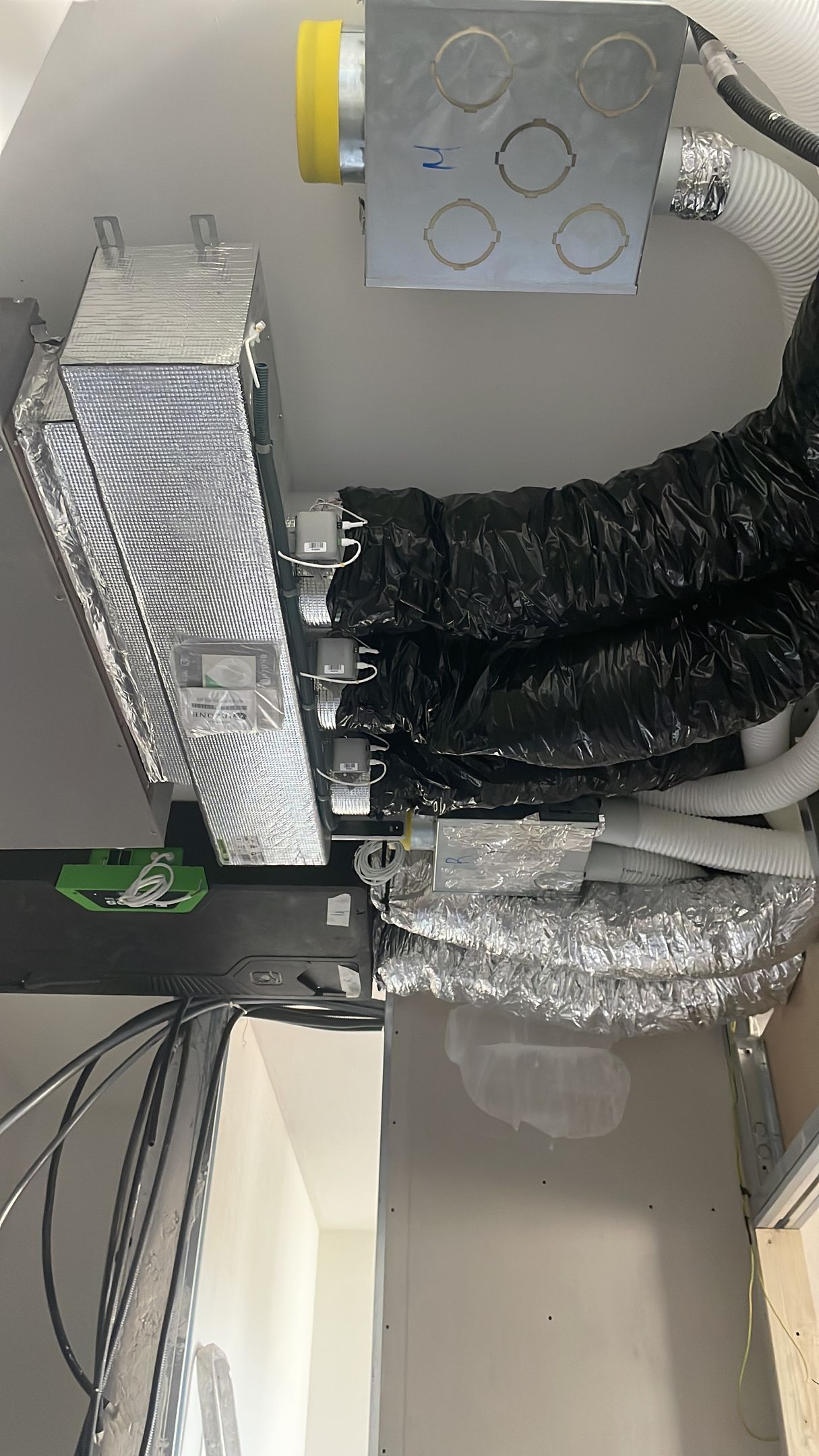 Condotti di climatizzazione a vista e tubi isolati in un vano tecnico a soffitto