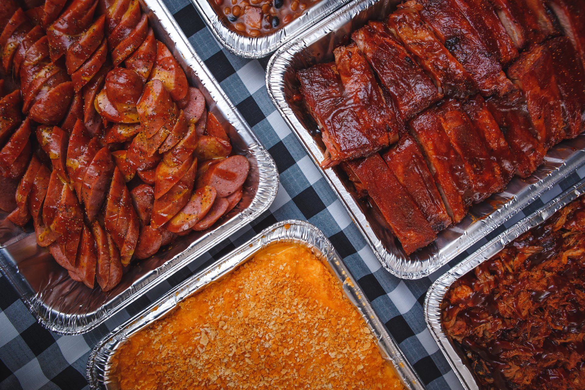 A bunch of trays of food are sitting on a table.