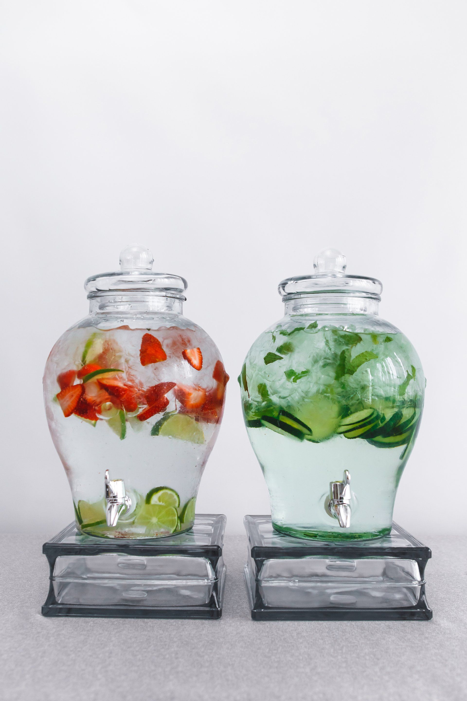 Two glass jars filled with fruit and ice are sitting on a table.