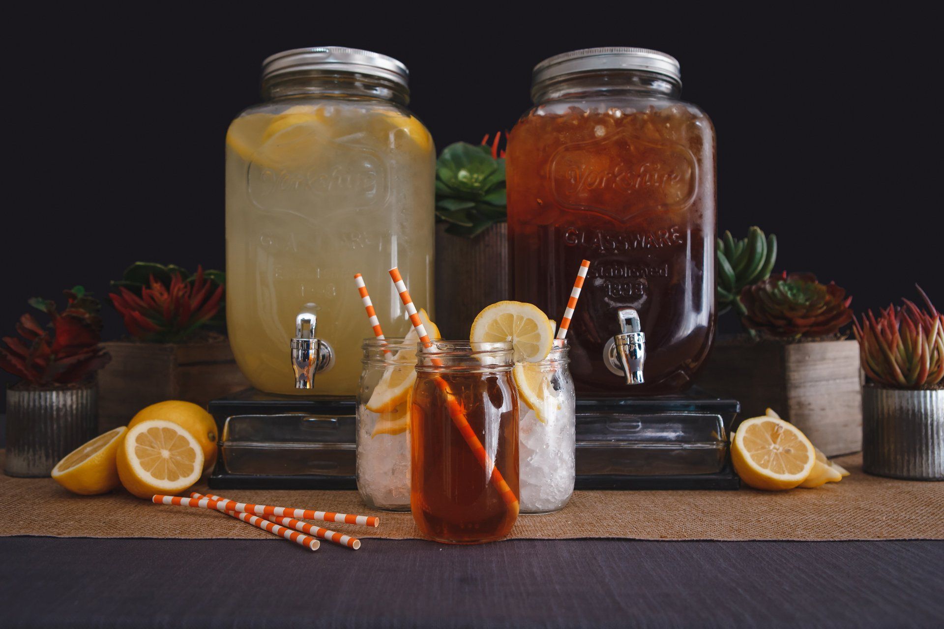 There are two jars of lemonade and iced tea on the table.