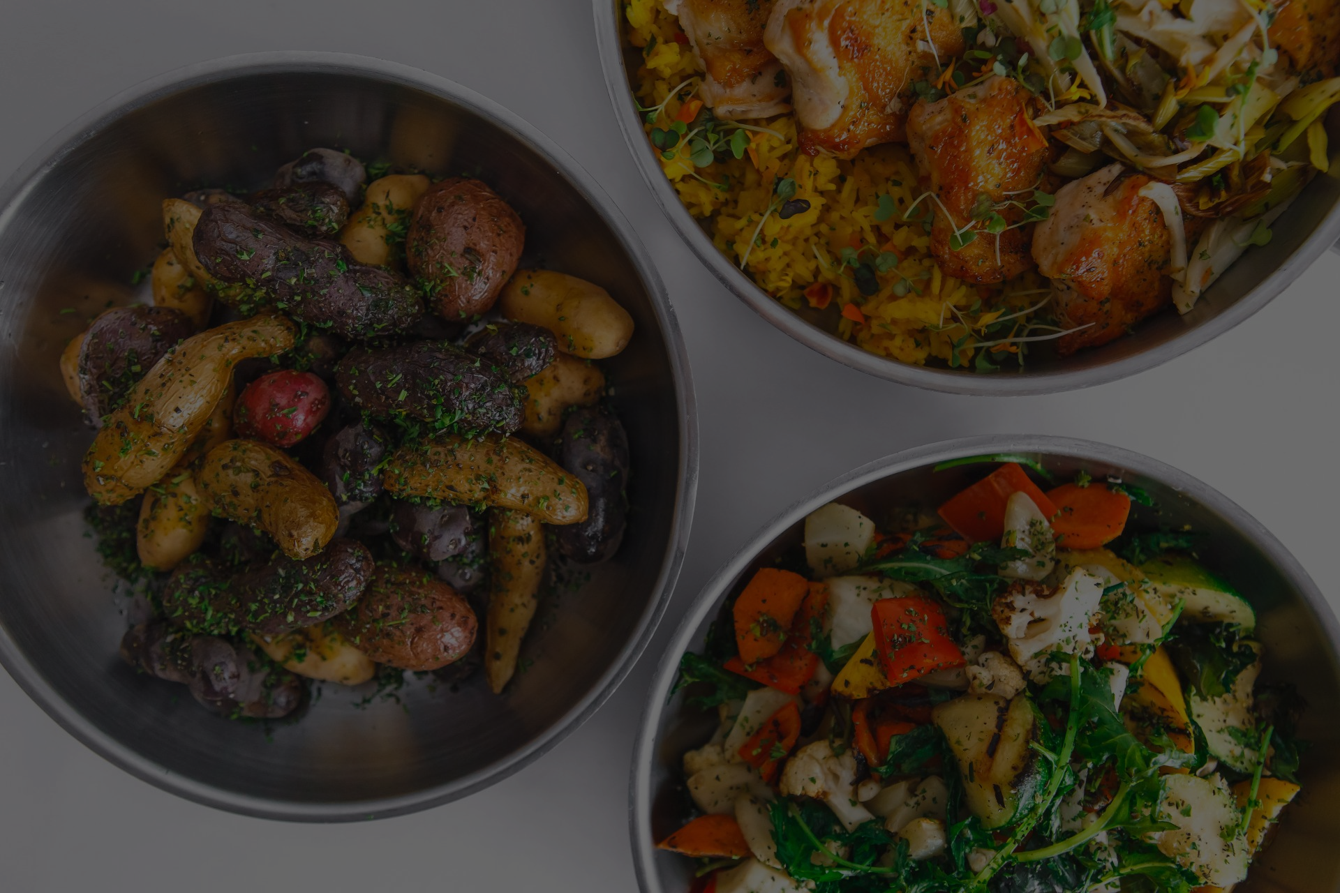 Three bowls of food are sitting on a table.