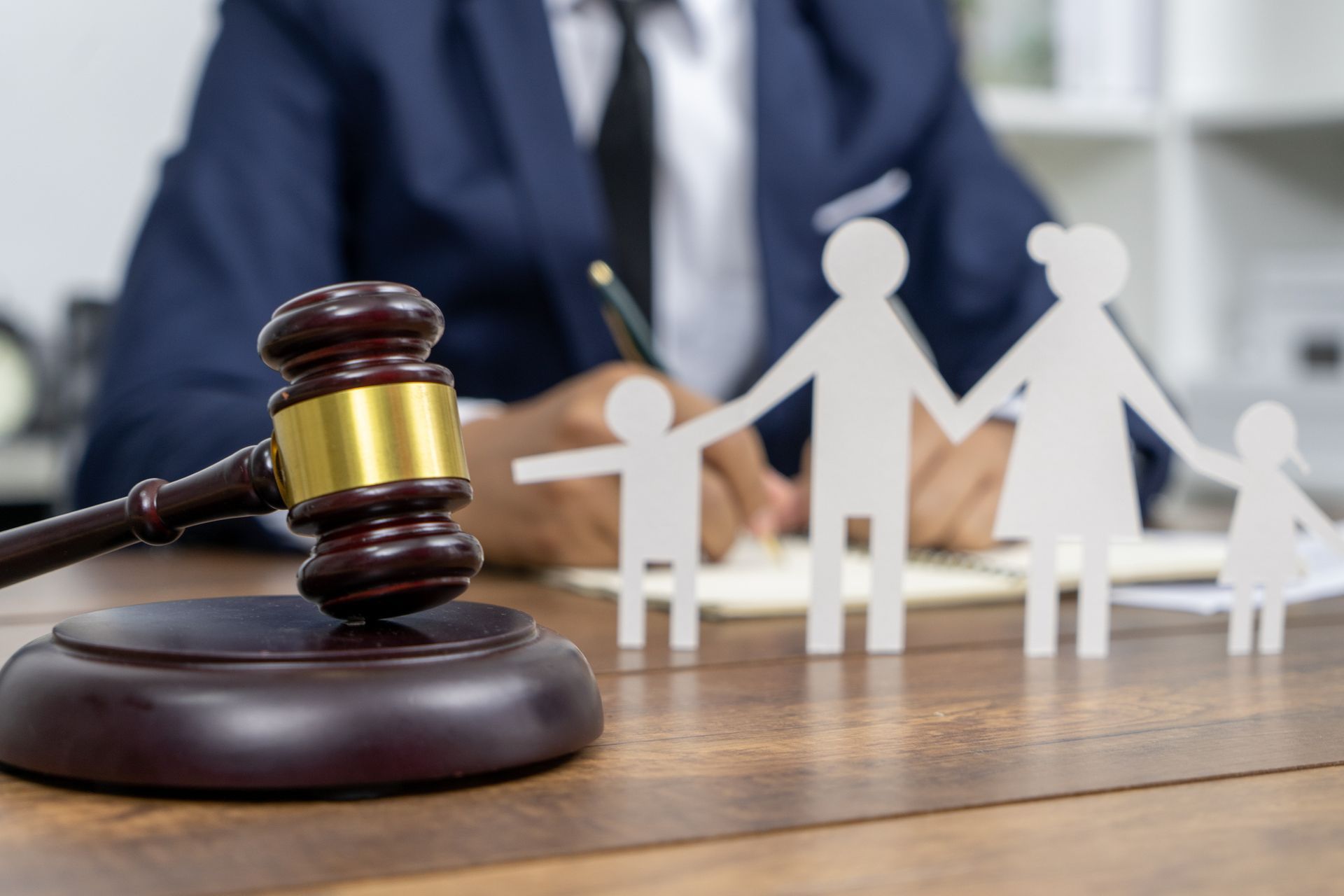 A judge is sitting at a table with a wooden gavel and paper cut outs of a family.