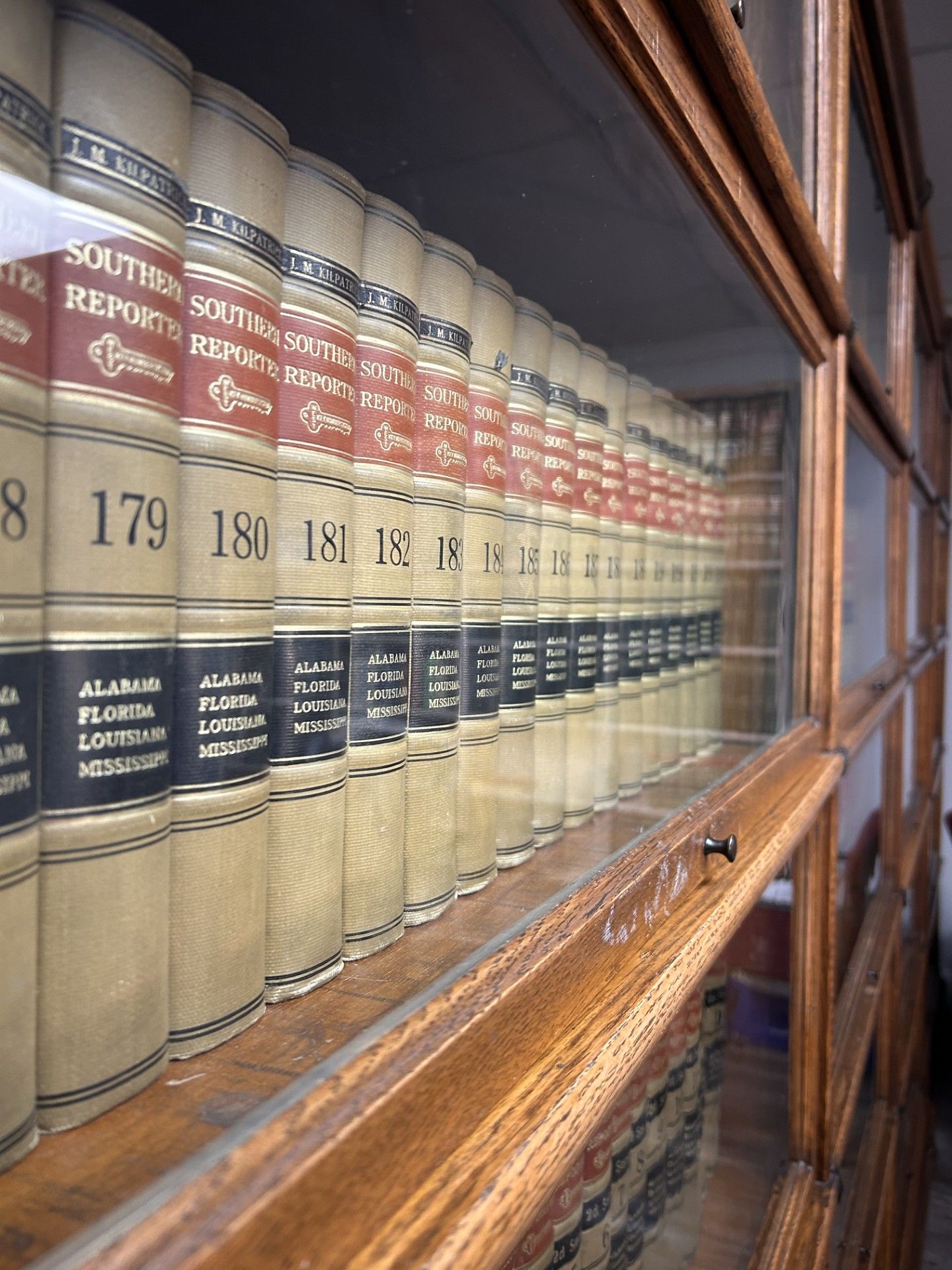 A row of law books are lined up in a glass case.