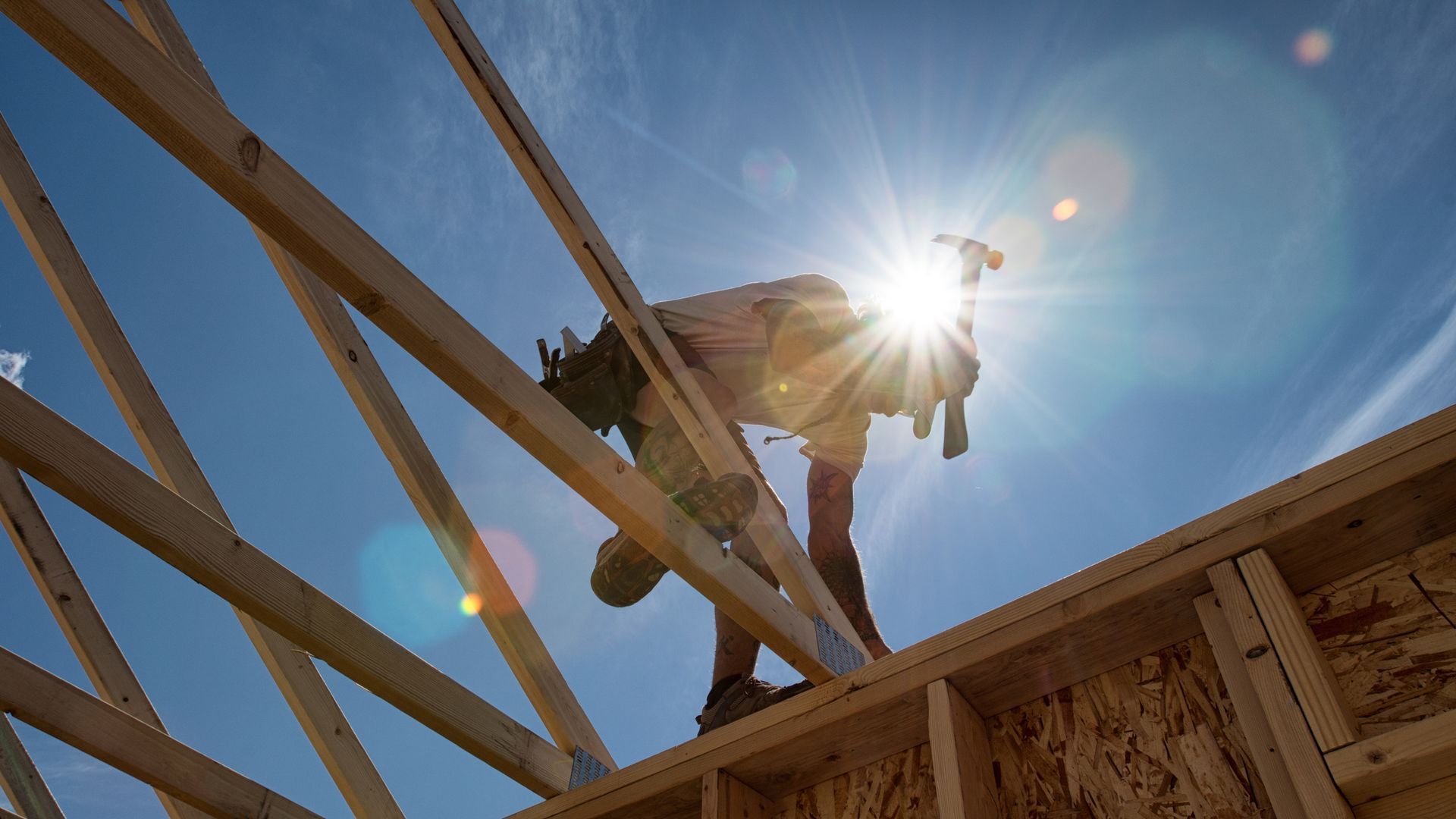 A construction worker is working on the roof of a house under construction.