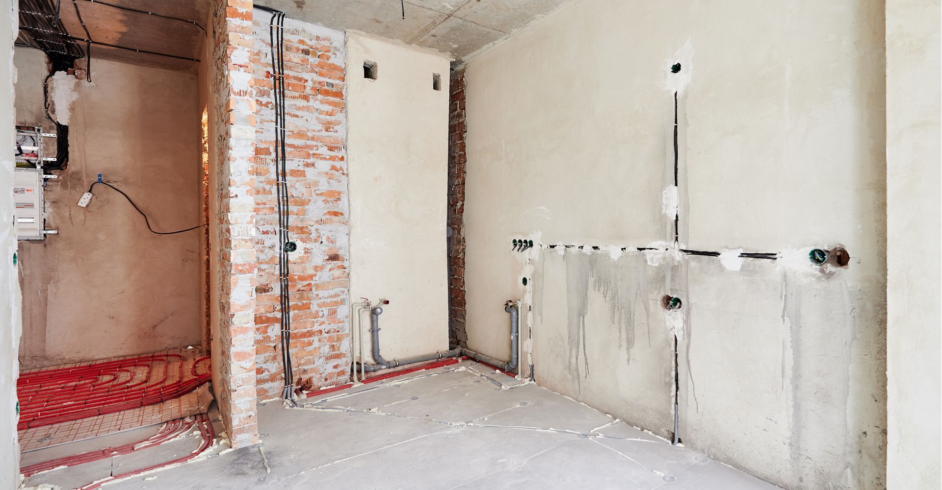 An empty room with a brick wall and electrical wires