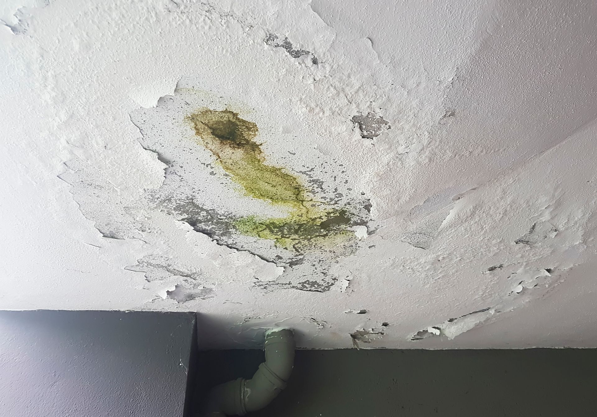 A ceiling with a hole in it and a pipe coming out of it.