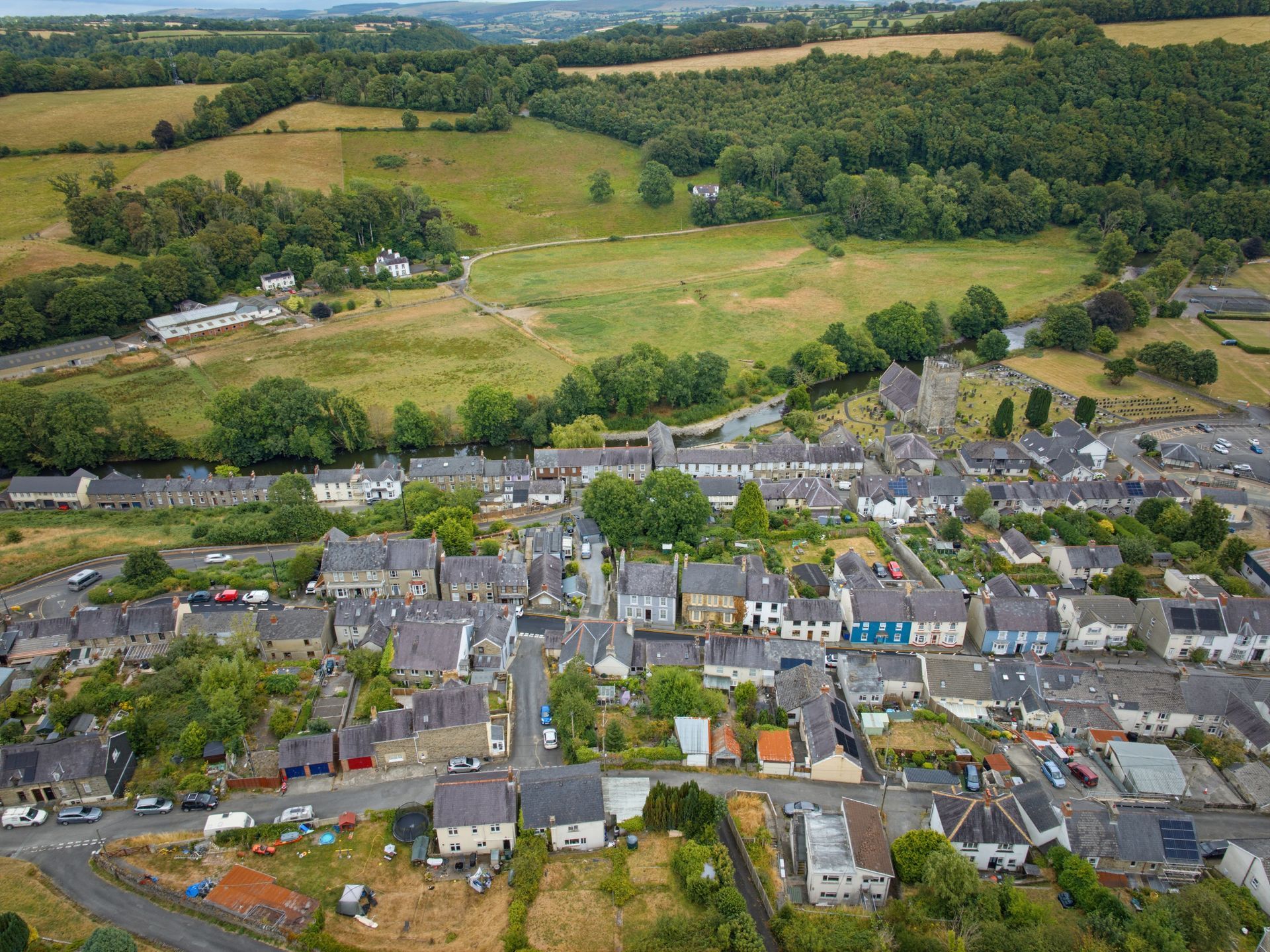 Aerial view of a small village with houses, roads, and green fields beyond it