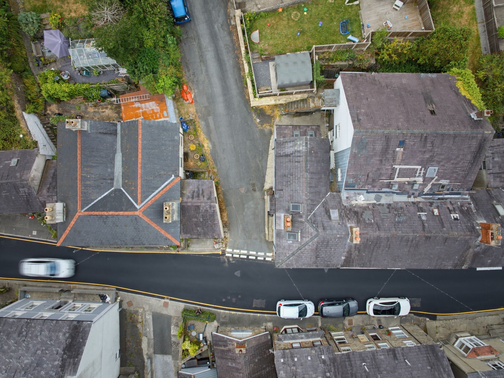 Aerial view of a residential street with parked cars and two houses