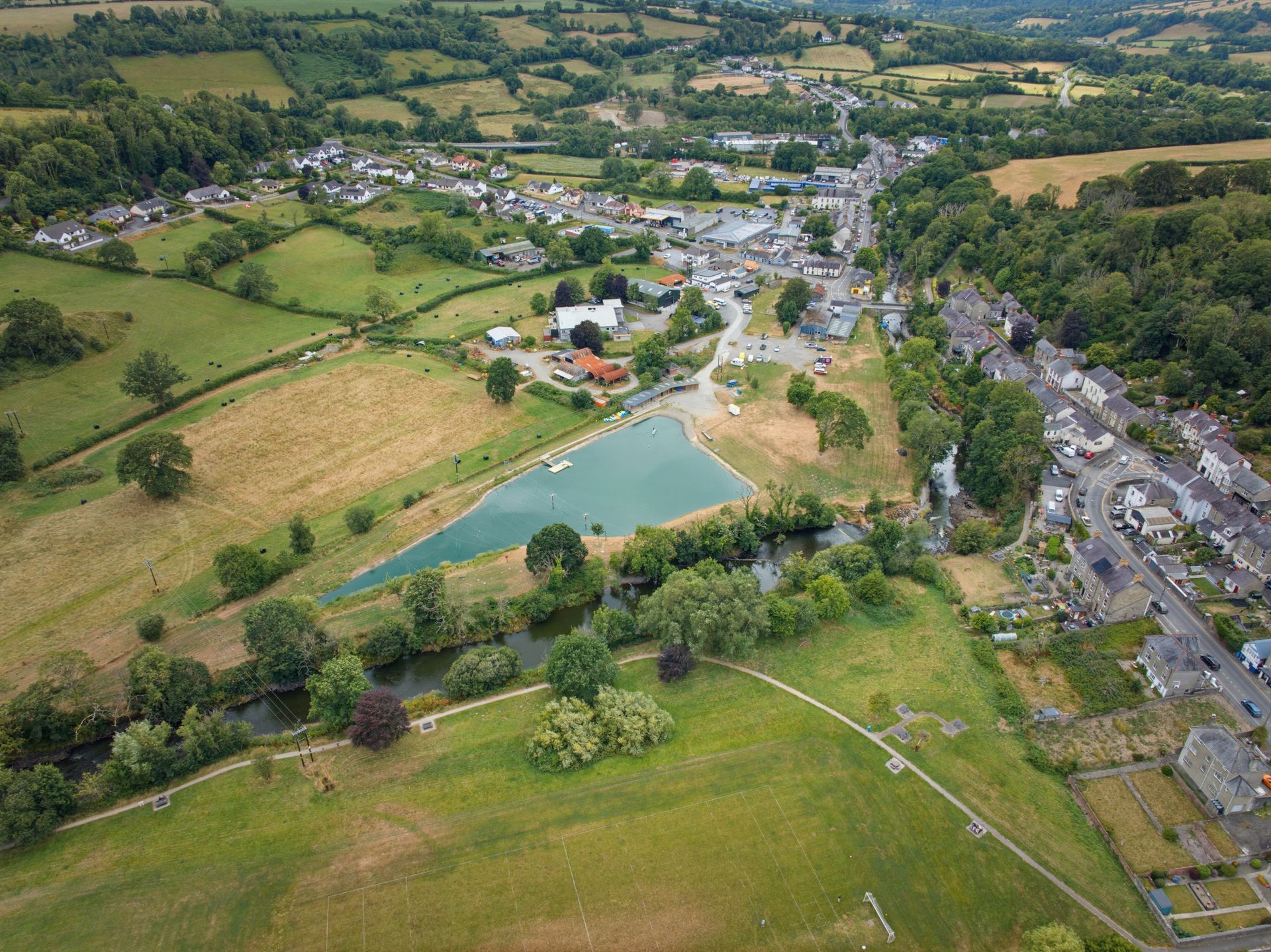 Aerial view of a rural village with fields, houses, roads, and a pond.