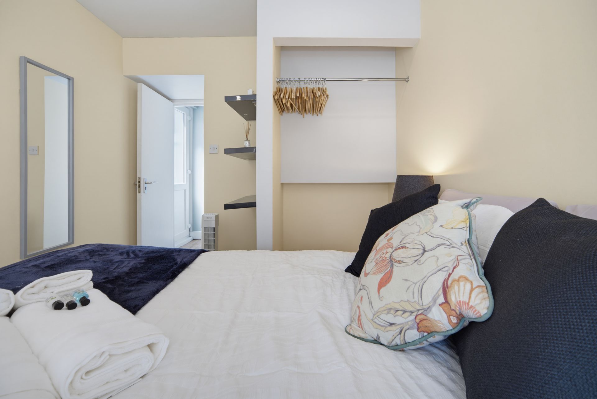 Neat bedroom with a bed, pillows, mirror, open closet, and warm lamp light