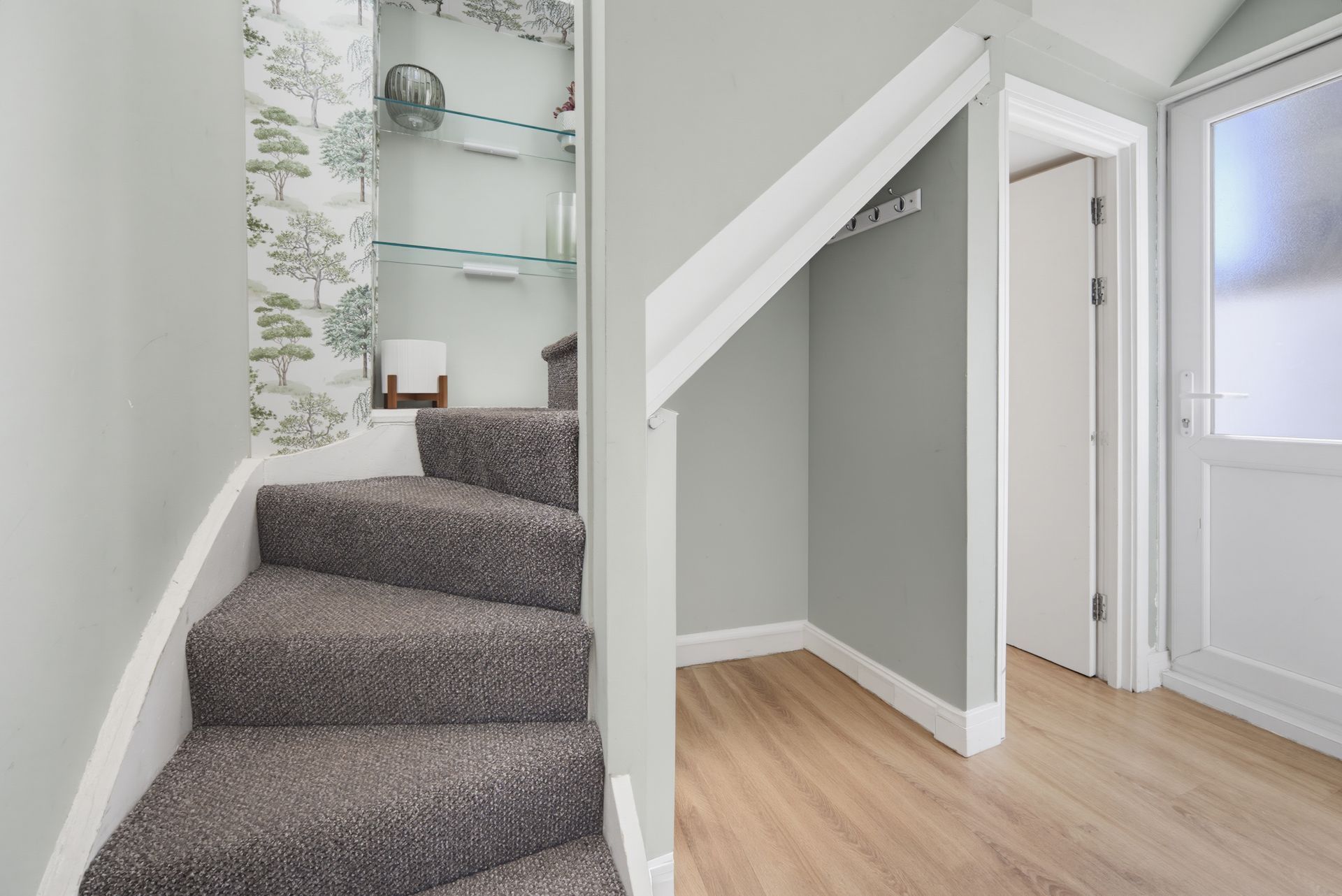 Carpeted staircase beside a hallway with light wood flooring and white doors.