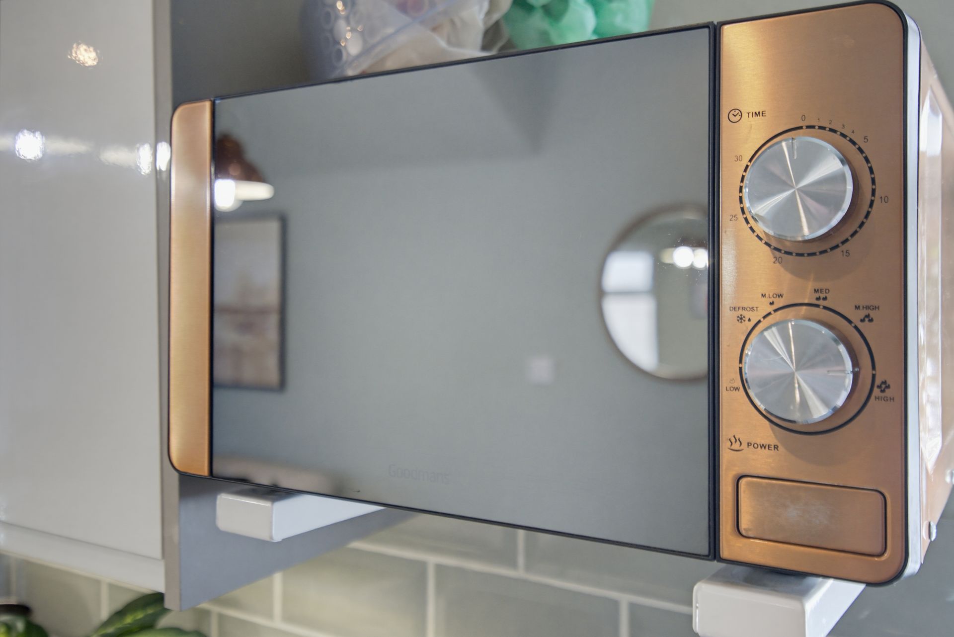 Vintage microwave oven with gold side panels and two silver dials on a kitchen counter.