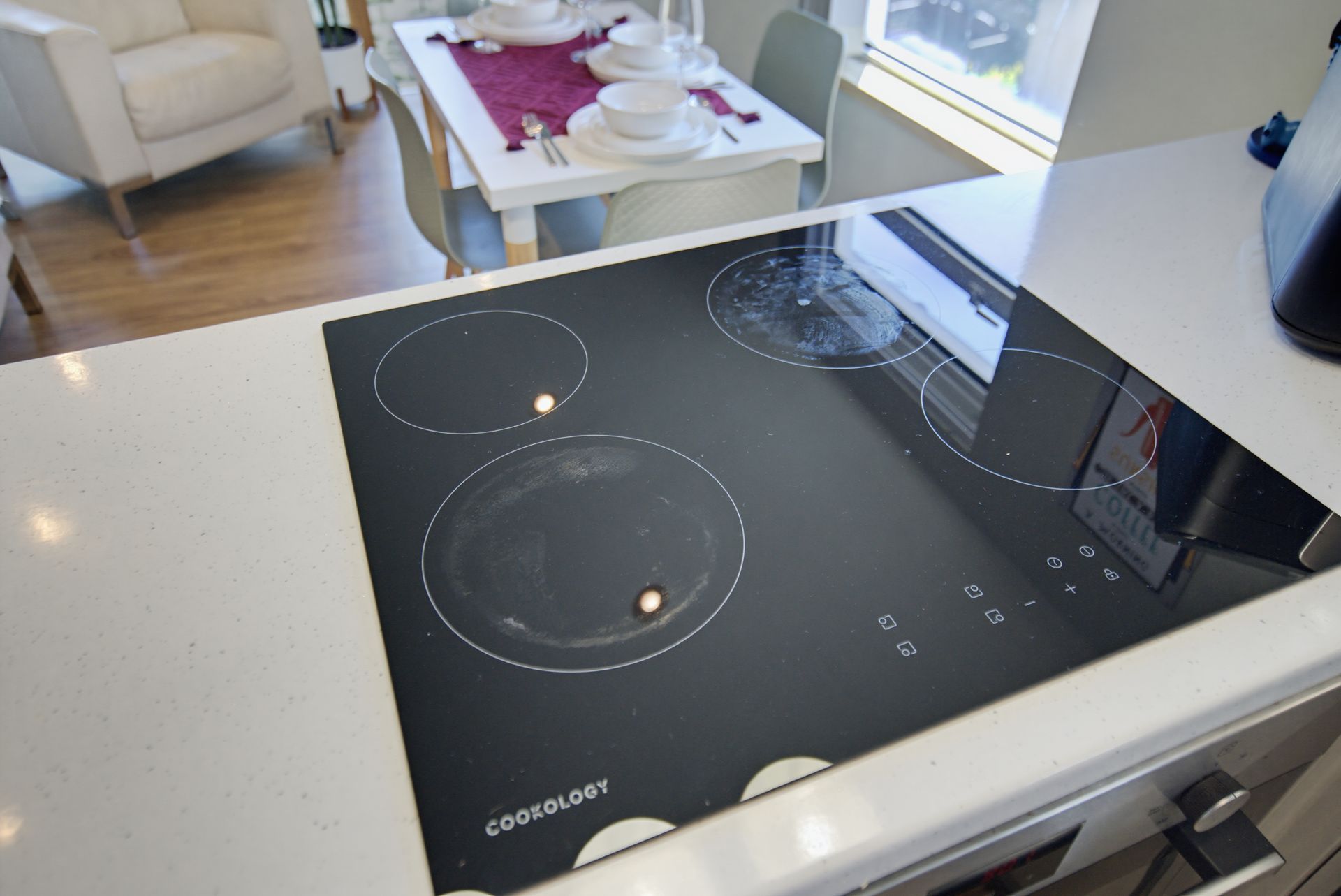Modern black glass cooktop in a bright kitchen with a dining table in the background