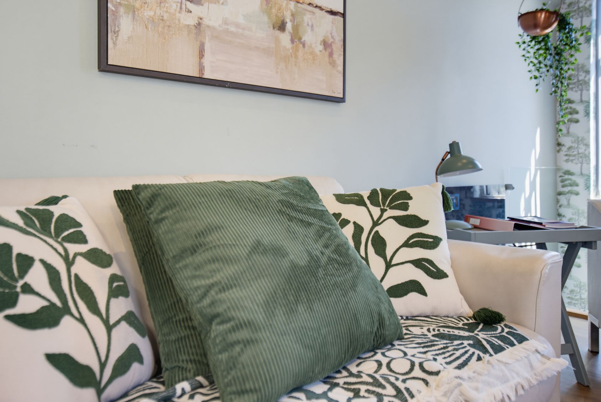 Green-patterned sofa with leafy pillows in a bright, modern living room