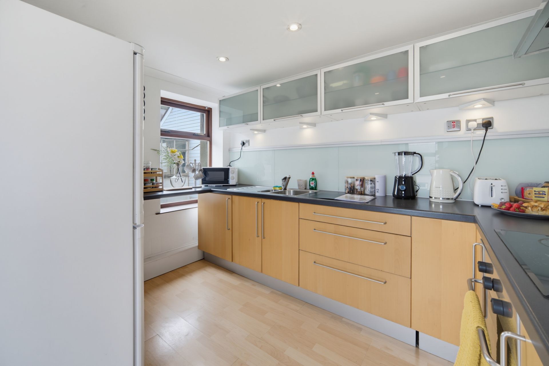 Bright modern kitchen with wood cabinets, gray countertops, and white upper cabinets