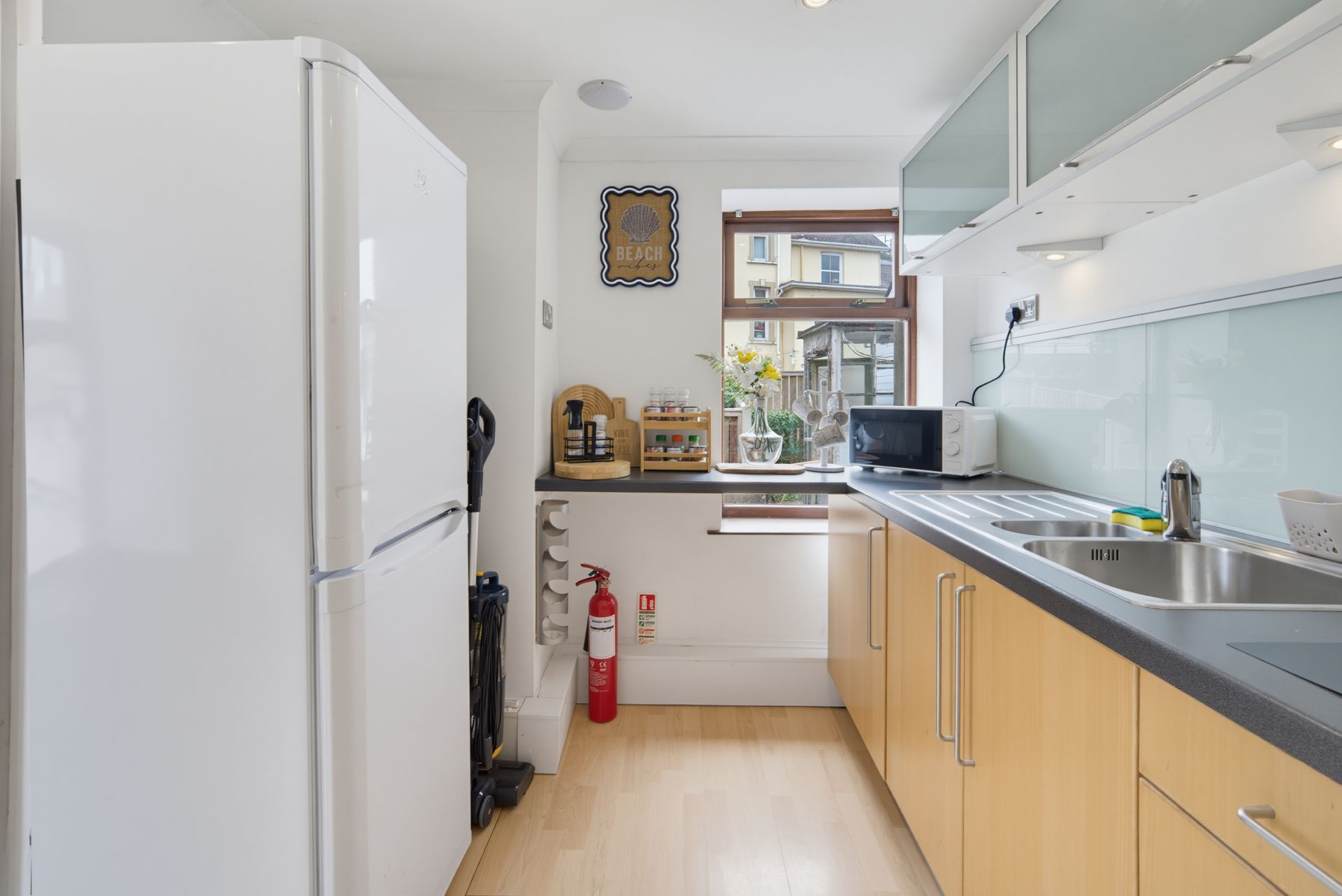 Bright modern kitchen with white cabinets, wood counters, and a window at the end.