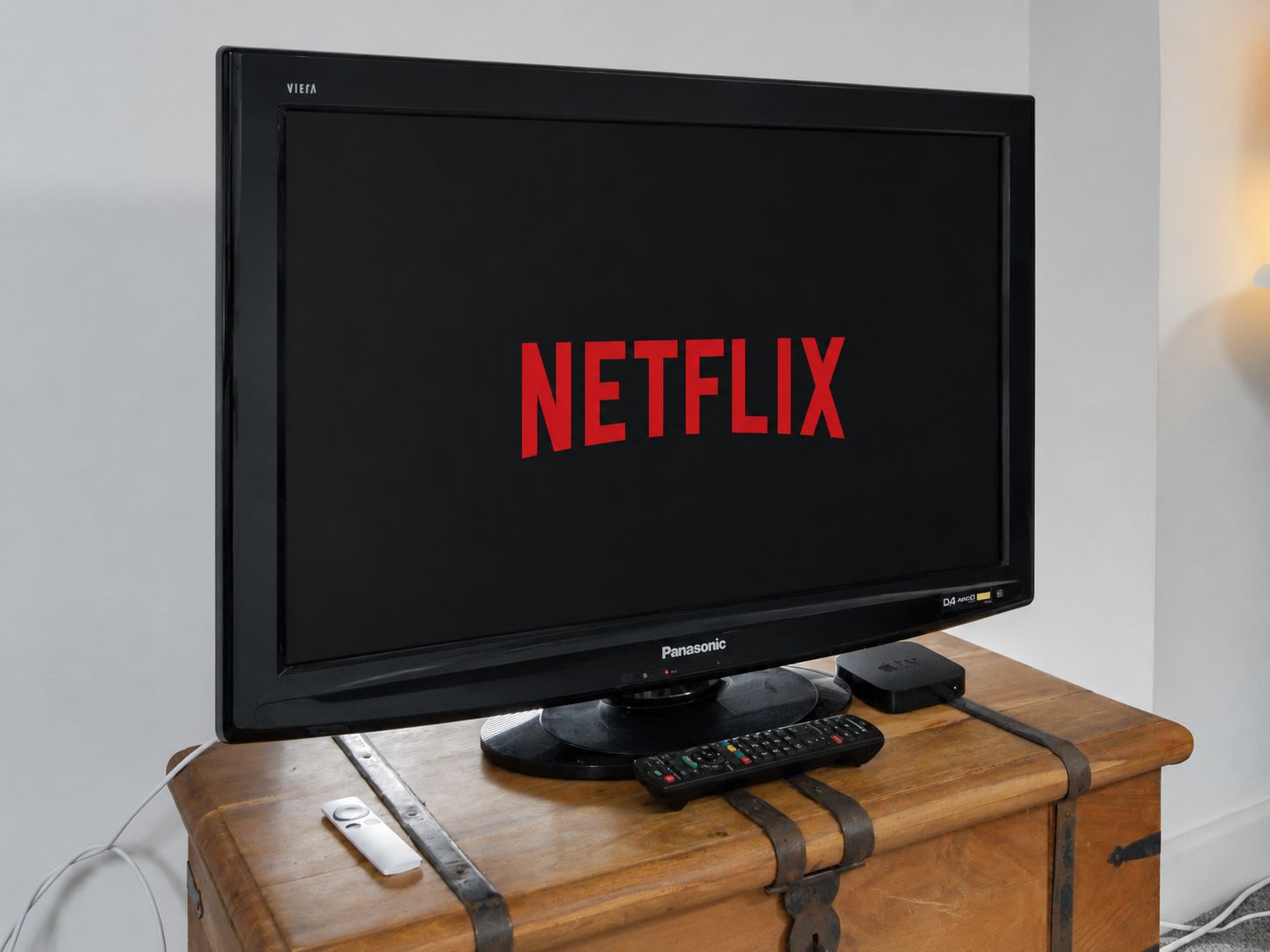 Black TV displaying Netflix logo on a wooden trunk in a room