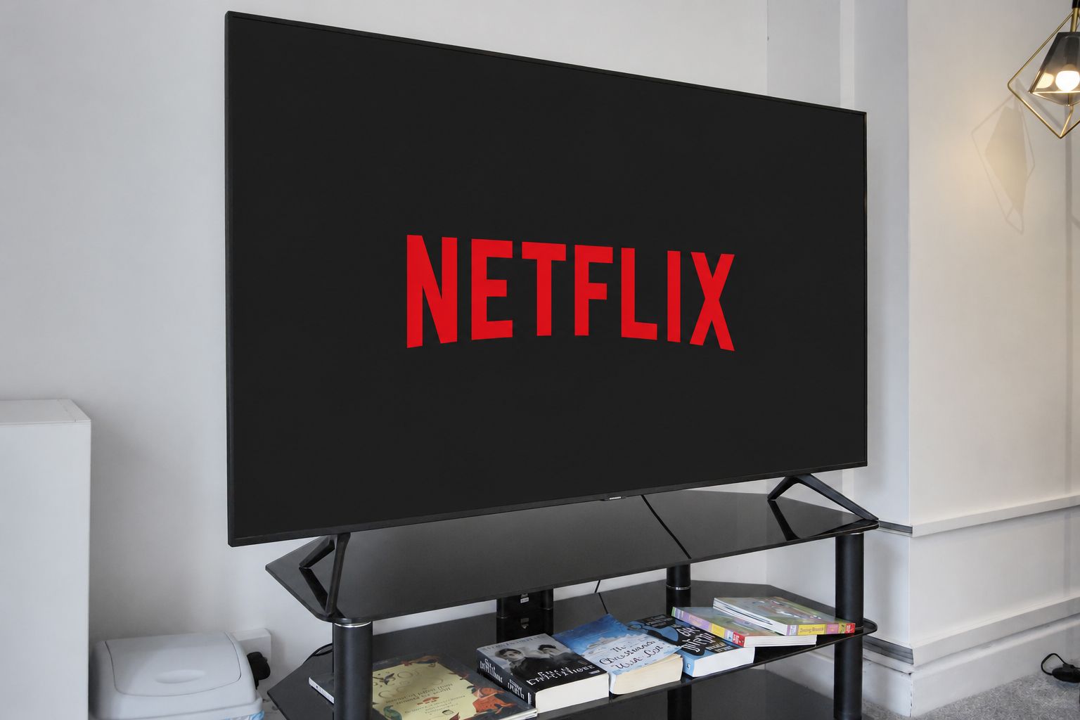 Netflix logo on a TV in a minimalist living room, with a black stand and books underneath