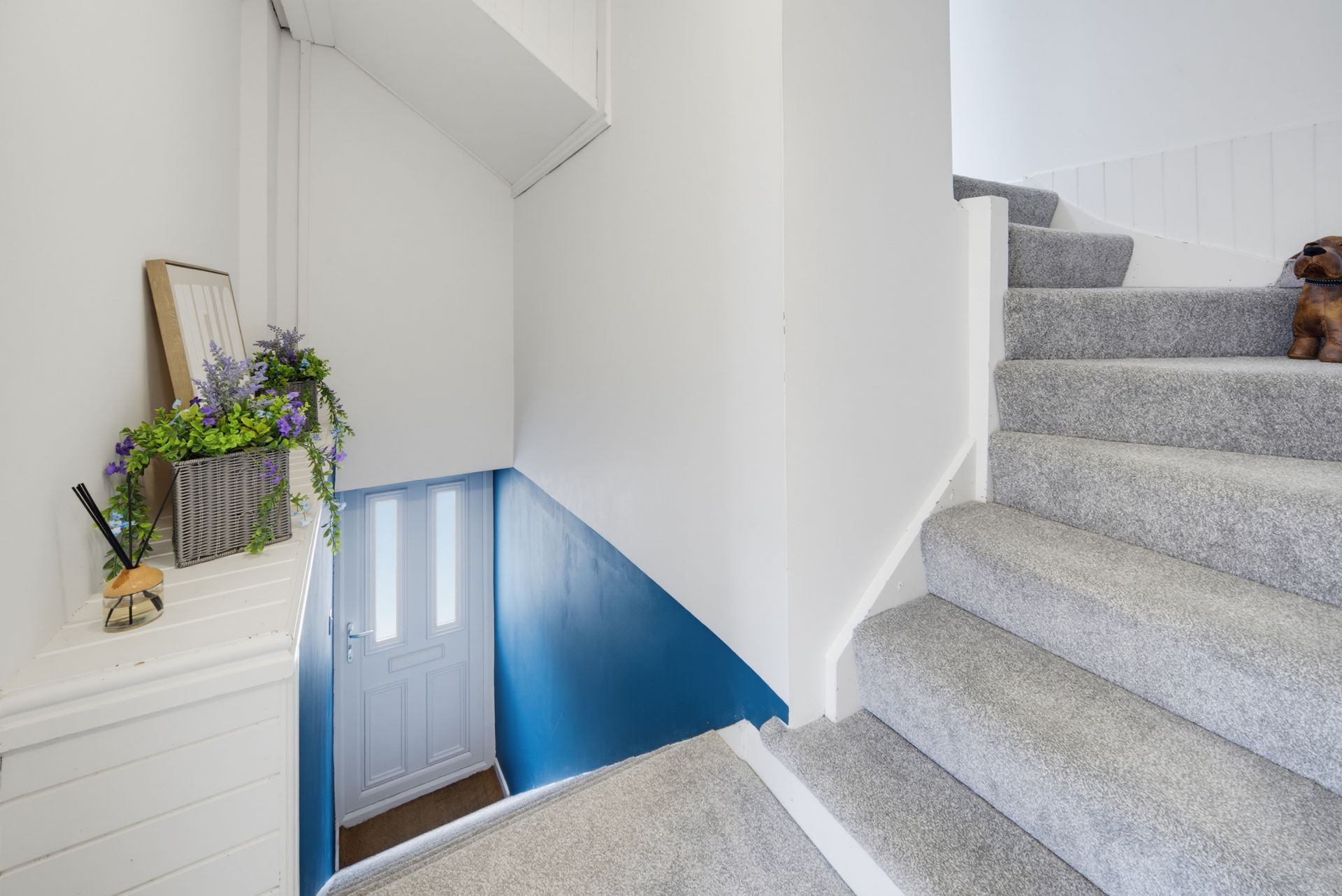 Interior stairwell with gray carpeted stairs and a blue-painted landing below.