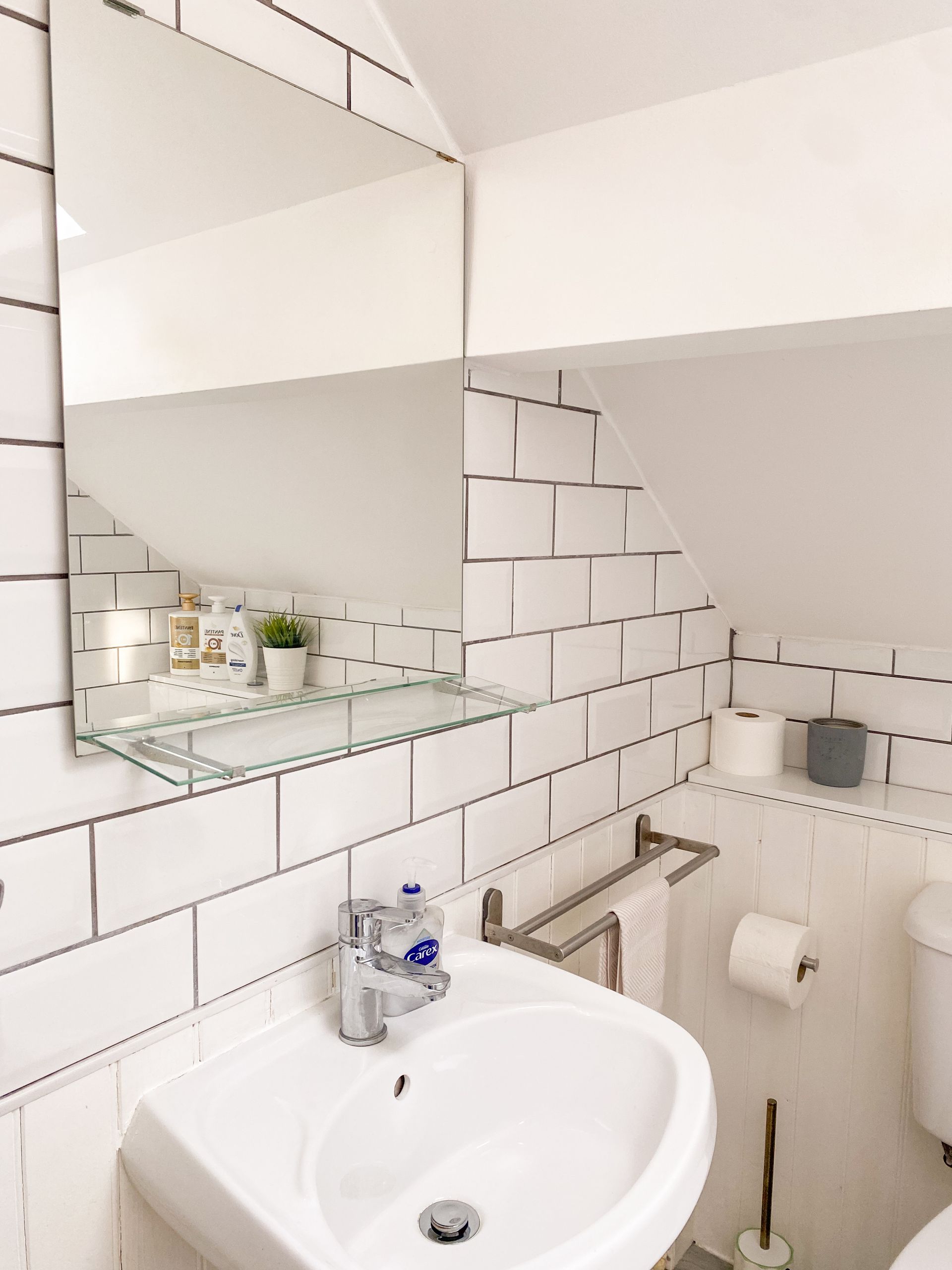 Small white bathroom with sink, mirror cabinet, toilet paper holder, and tiled walls