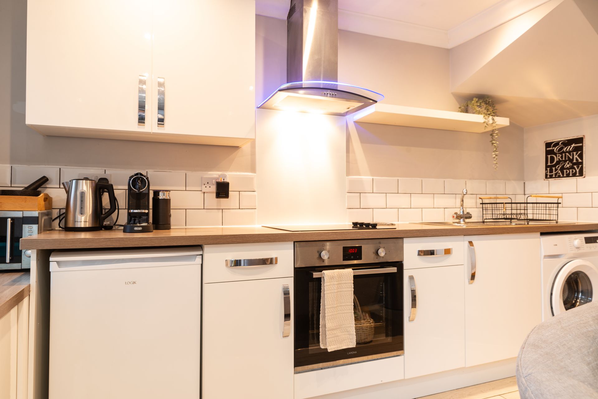 Bright modern kitchen with white cabinets, wooden countertops, stainless range hood, and appliances
